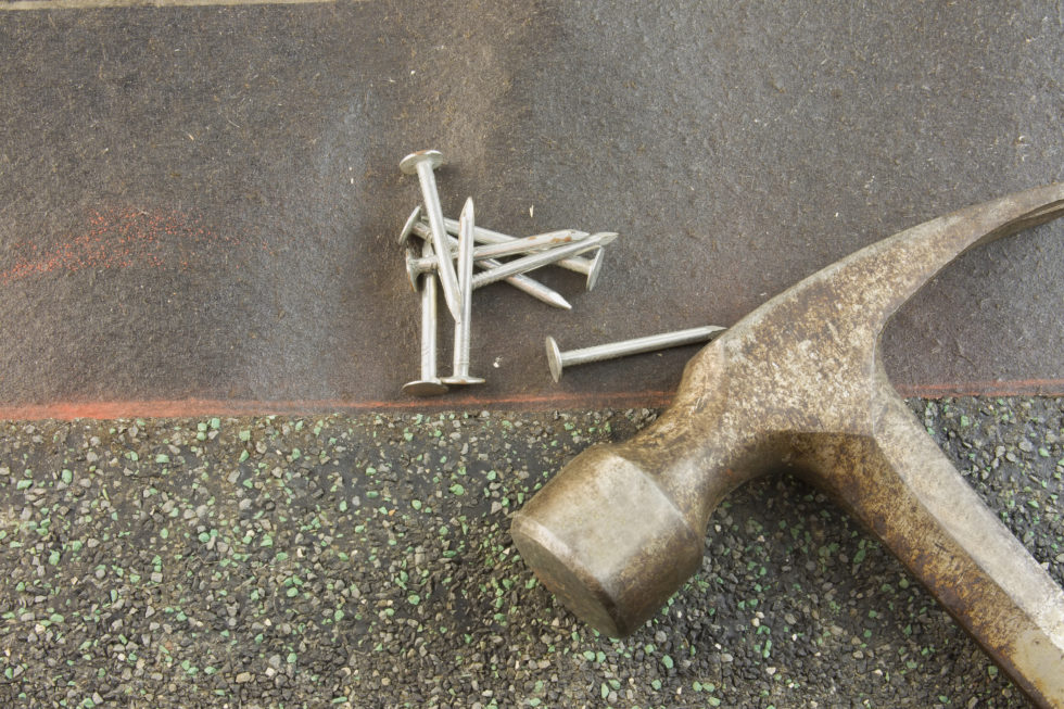 Photo of hammer, nails and roofing material