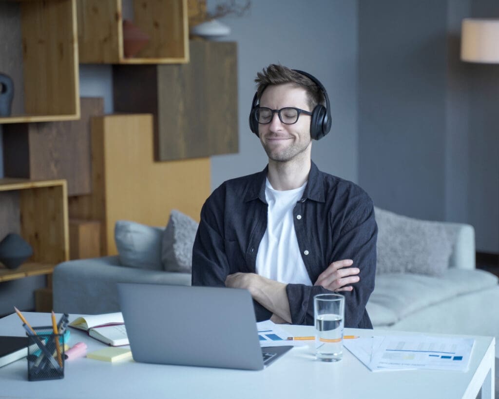 man listens podcasts or audiobooks on headphones during remote work on laptop