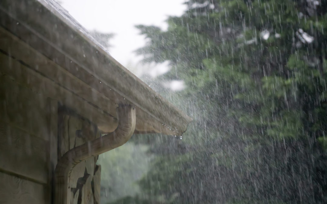 heavy rain pouring down from passing storm into rain gutters to illustrate How Often to Replace Gutters