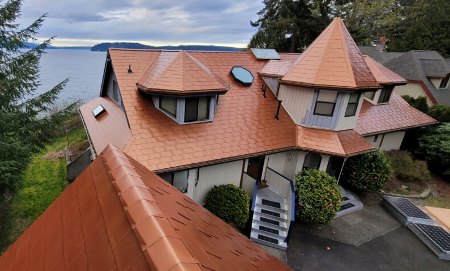 A beautiful home on the shoreline with copper roofing to help illustrate does coastal metal roofing make sense.
