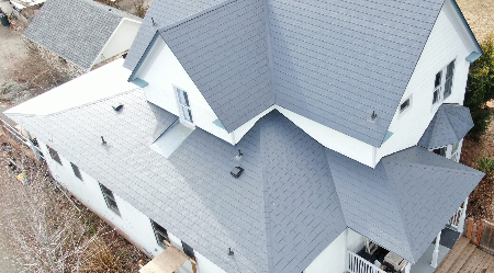 A newly installed metal roof on a two-story white house to help illustrate closure strips for metal roofing.